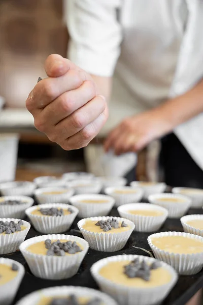 Unrecognizable baker woman adding chocolate on top of a cupcake mold