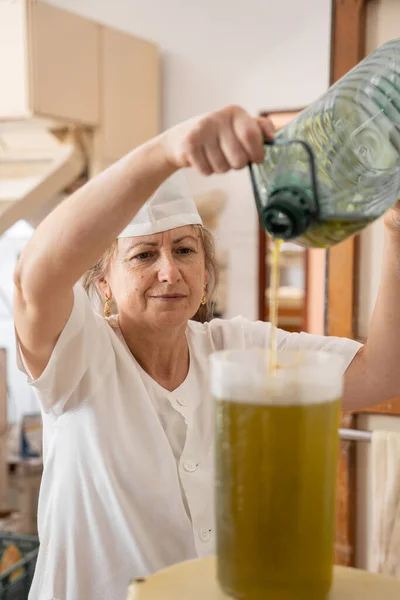 Baker woman pouring oil into a pitcher in order to prepare cupcakes