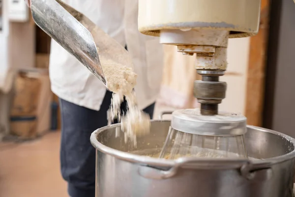 Tanınmayan fırıncı kadın sanayi atıcısına un ekliyor.