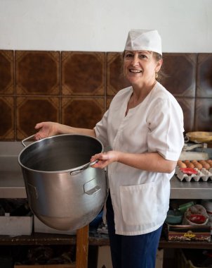 Fırıncı kadın fırın tavasıyla gülümsüyor.