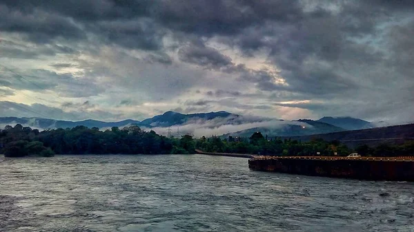 Плотина Вода Течет Облачной Погодой Горами Позади Мост Дамбы — стоковое фото