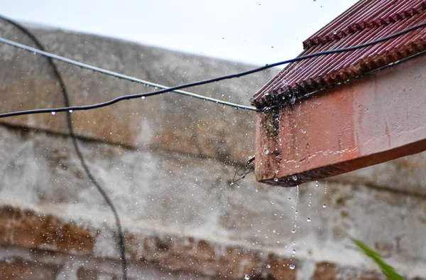 Rain drops falling from top of the house.