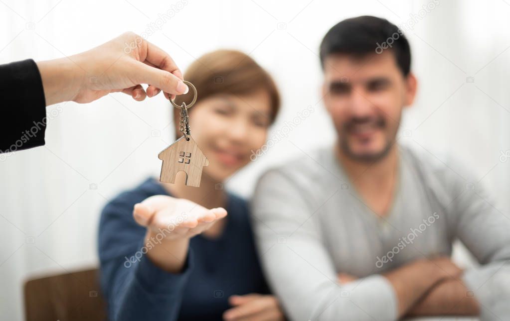 Real Estate Agent giving key of new house to Young couple. Happy man and woman smiling.