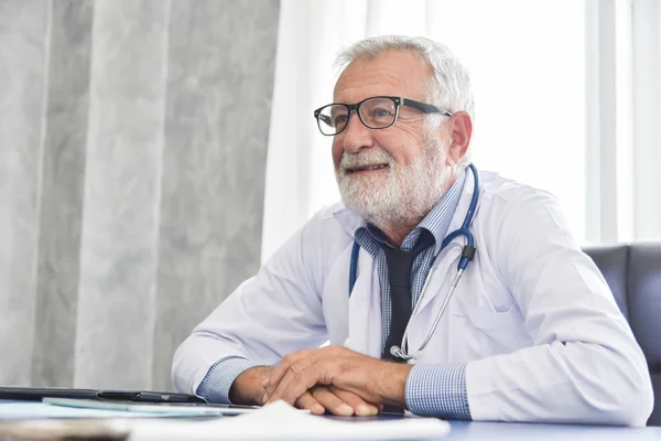 Portrait of Confident Senior male Doctor is sitting and smiling in a medical room.  Successful. Happiness.