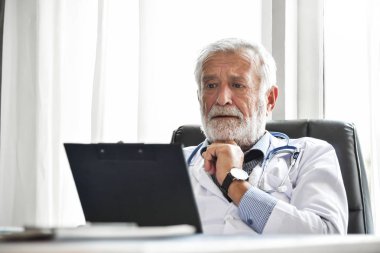 Üst düzey erkek doktor düşünme ve bir panosuna bir hastanede hasta tıbbi kayıtlarını kontrol. Tıbbi ve sağlık kavramı. Vurguladı. Endişeli. Konsantrasyon.