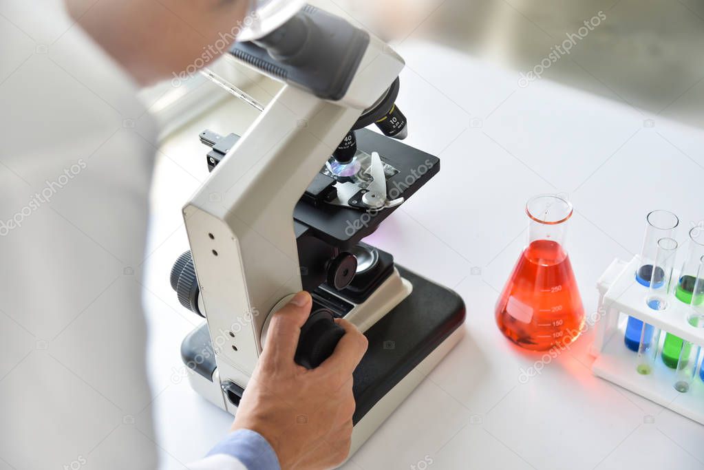 Young Man scientist looking through a microscope in a laboratory. Research.