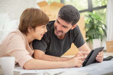 Mutlu genç çift dijital tablet ve onların yeni ev taşıma planlama planları ile. Birbirimizi gülümseyen.