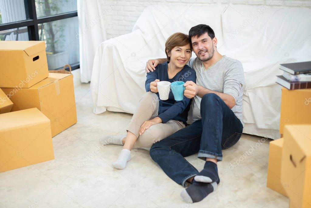 Happy Young Couple holding cups of coffee at their new home. Moving house day.