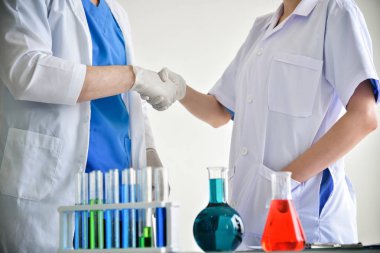 İki bilim adamları laboratuarda el sıkışma vardır.