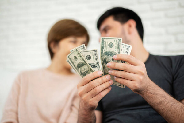 Счастливая молодая пара считает деньги, сидя на диване для своего нового дома. Экономия
.