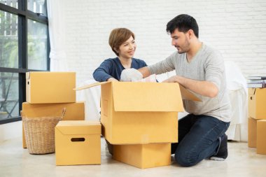 Mutlu genç çift yeni evde karton kutuları açma. Ev taşıma.