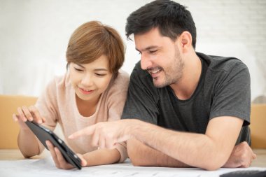 Mutlu genç çift dijital tablet ve onların yeni ev taşıma planlama planları ile. Gülümseyen yüzler.