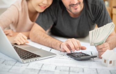 Para tutan ve ev taşıma kendi bütçe hesaplama dizüstü bilgisayar ile mutlu genç çift.