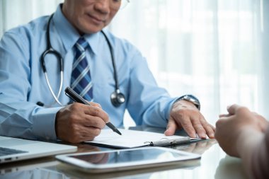 Mavi gömlekli bir şey onun hasta, sağlık odası ile konuşurken Panoda yazıyor Asya kıdemli erkek doktor.