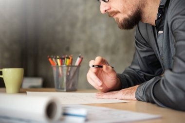 Evrak işlerini yeni proje için yeni fikirler çizim ile çalışan konsantre erkek mimar tasarımcı. 