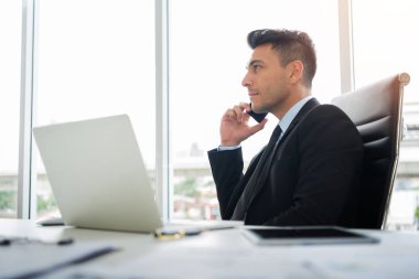 Konsantre işadamı ofiste cep telefonu kullanıyor.