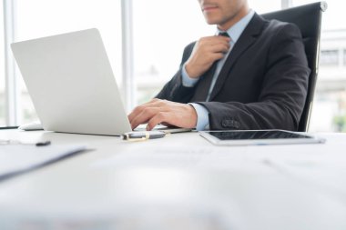 Kendine güvenen işadamı ofiste dizüstü bilgisayar üzerinde çalışıyor.