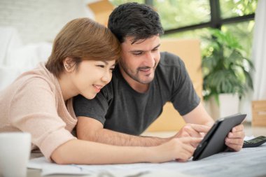 Mutlu genç çift dijital tablet ve onların yeni ev taşıma planlama planları ile. Gülümseyen yüzler.