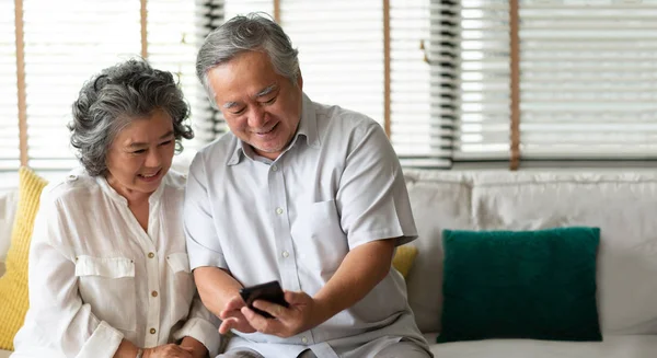 Boldog Ázsiai Idősebb Pár Smartphone Technológiával Miközben Mosolyogva Otthon Fotelben — Stock Fotó