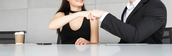 Businesswoman and Businessman in black suits are making fits bump during talking in office. Successful Teamwork in a meeting. Panoramic, Banner with copy space for web.