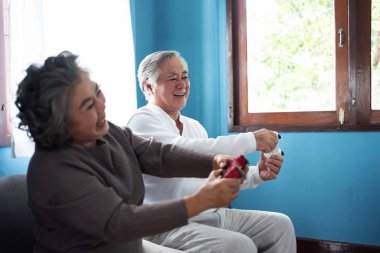 Oyun oyun çubukları ile oturma içinde neşeli Asya kıdemli çift.