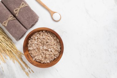 Spa ürünleri. Tuzları içinde havlu, tahta kaşık ve kulakları arpa ile yuvarlak şeklinde ahşap tepsi üst bakış beyaz mermer zemin üzerinde. Kopya alanı.