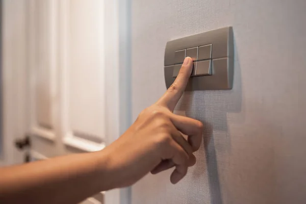 Asian female right hand is turning off on grey light switch. — Stock Photo, Image