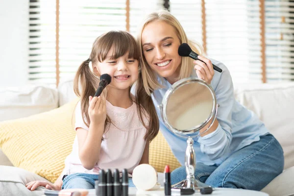 Mother and daughter applying cosmetic.