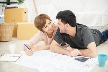 Mutlu genç çift yeni evleri planlama planları ile.