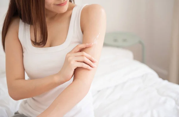 Mujer aplicando loción corporal en su brazo . — Foto de Stock