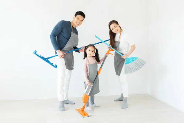 Happy Asian Family dancing and holding cleaning equipment.