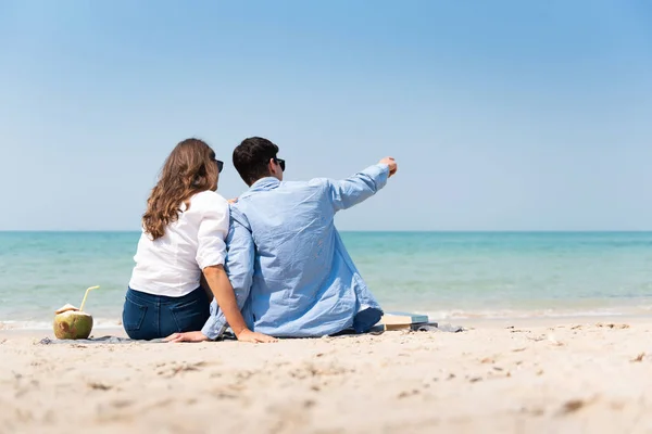 Casal em casual sentado na areia na praia — Fotografia de Stock