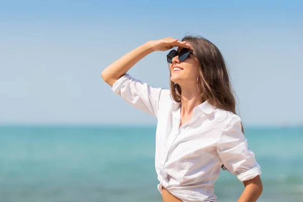 Mujer en gafas de sol sonríe sobre el cielo azul . — Foto de Stock