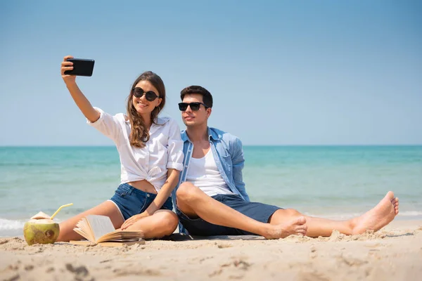 微笑的年轻夫妇在海滩上自拍. — 图库照片