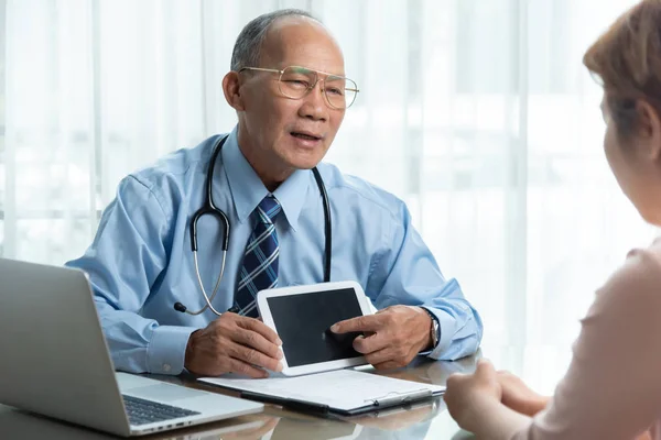 Asiático Senior Médico en camisa azul hablando con su paciente . — Foto de Stock