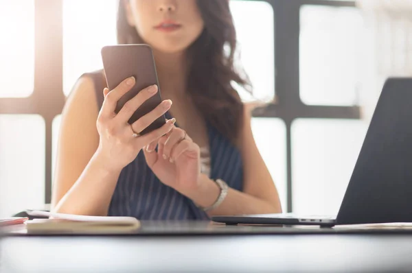 Asian Female is using mobile phone for contacting her customer.