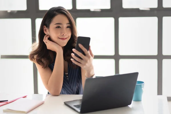 Sorrindo Mulher de negócios está segurando e olhando para seu smartphone . — Fotografia de Stock
