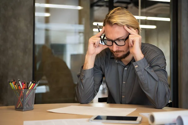 Diseñador creativo masculino estresado sentado y pensando . — Foto de Stock