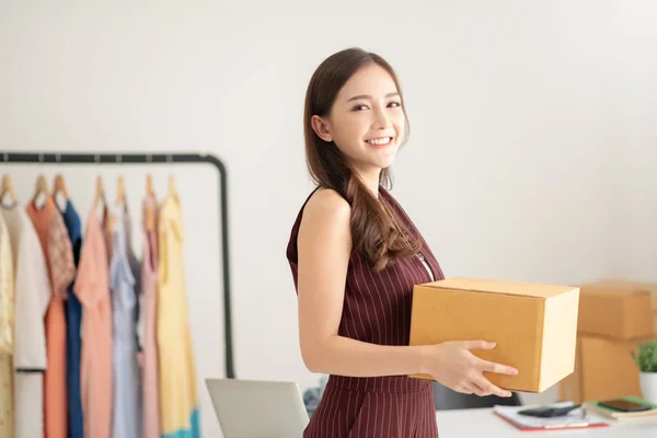 Mulher designer de moda de pé e segurando caixa de papelão . — Fotografia de Stock