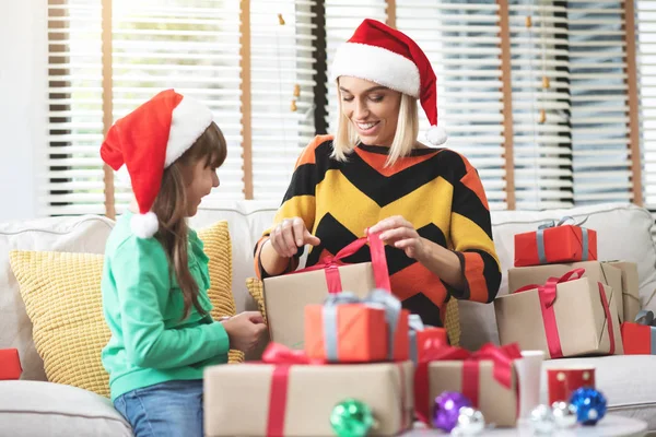 Junge Mutter und ihre Tochter packen Geschenk oder Geschenkbox aus — Stockfoto