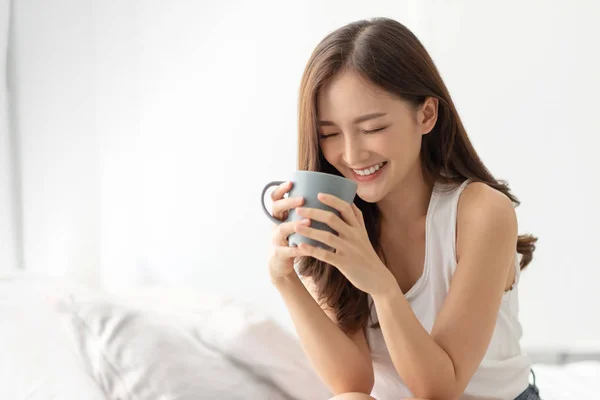 Feliz joven asiática mujer es relajarse con una taza de bebida caliente . —  Fotos de Stock