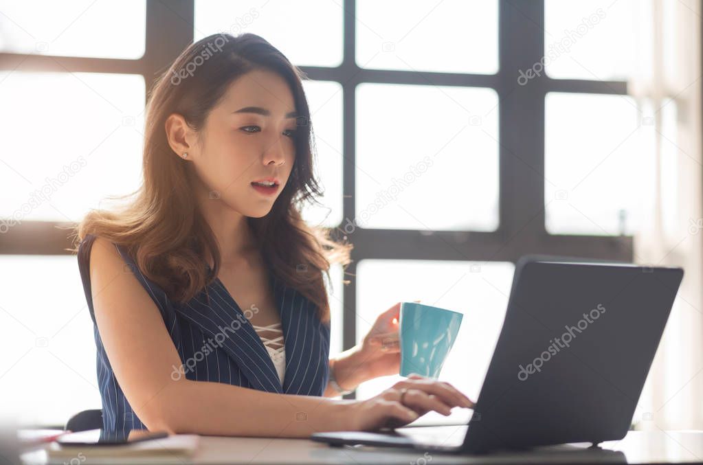 Young Asian female sitting and using Laptop computer in the offi