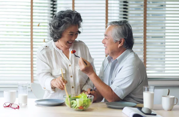 Heureux asiatique couple de personnes âgées faire et manger salade saine . — Photo