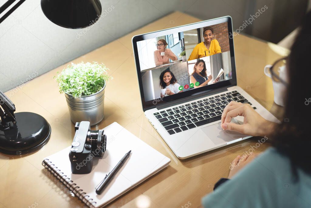 Multi ethnic Women colleague making video call for on laptop computer while work from home. Diversity Businesswomen partner team talking business via internet in a meeting at workplace.