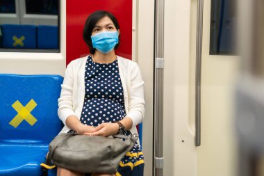 Şehirdeki metro ile işe giderken Asyalı kadın maske takıyor. Güzel genç bayan, banliyö treninde salgın virüsü, koronavirüsü ya da covid-19 'u korumak için koruyucu bir maske takıyor. Yeni normal