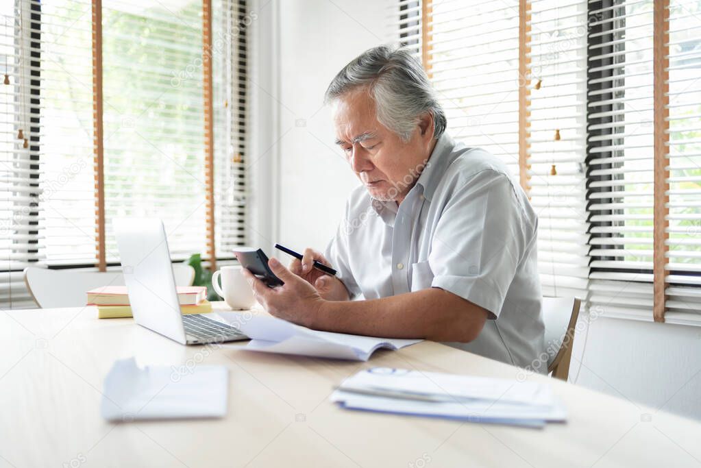 Worried Senior man having problem about Financial economic crisis. Stressed Asian Elderly male calculate family budget, Debts, monthly expenses with calculator and laptop computer at home