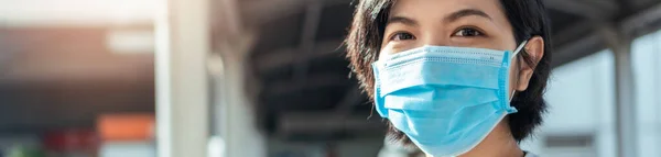 閉じるアップ若い美しいアジアの女性の顔を身に着けています青い保護顔マスクカメラを見て新しい通常の生活の中でアウトドア バナー ウェブ パノラマでパンデミックCovid 19またはコロナウイルス — ストック写真