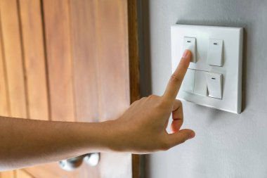 Evdeki ahşap kapının yanındaki ışıklandırma düğmesini kadın parmağının kapatması. Güç, Enerji, Elektrik Kaydetme, Boşluğu Kopyala.