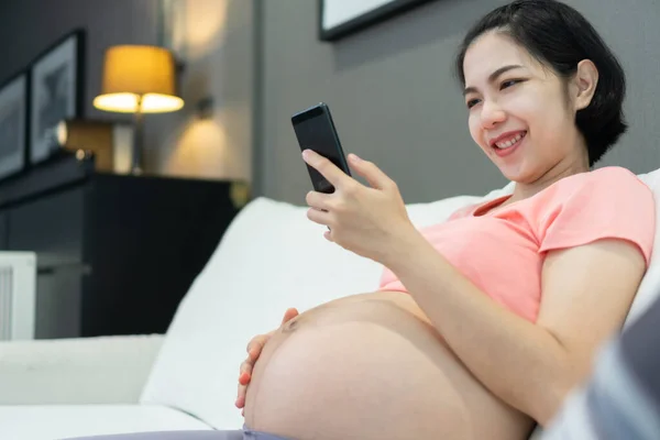 Glad Leende Asiatisk Mor Använder Mobiltelefon Medan Graviditeten Hemma Gravid — Stockfoto