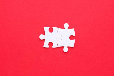 İzole edilmiş kırmızı arkaplanda iki yapboz parçası birleşiyor.